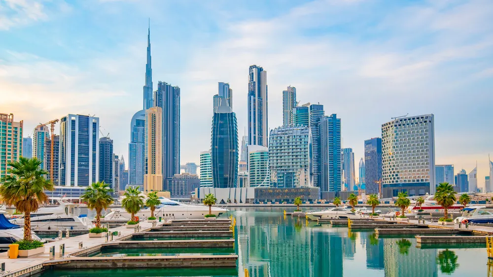Business Bay skyline reflected in marina with palm trees foreground