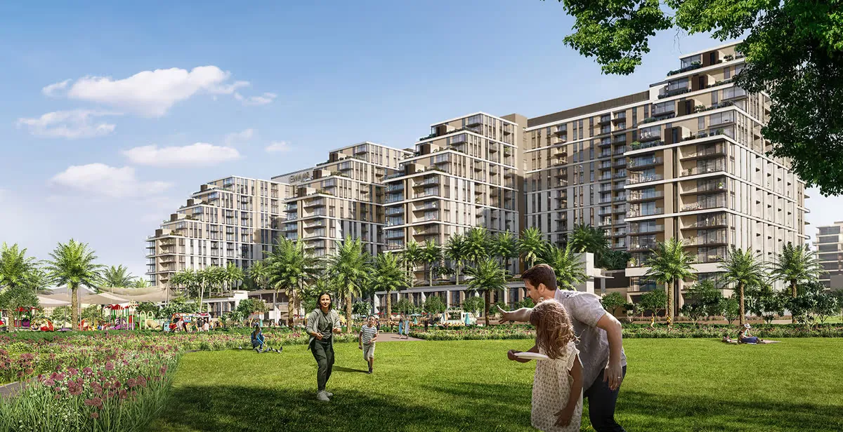 Family playing in Dubai Hills Park with EMAAR apartment towers in background